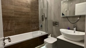 A modern bathroom with a large bathtub, a separate toilet, and a vanity with a sink. - Themed Stunning 1-bed Apartment in London (London)