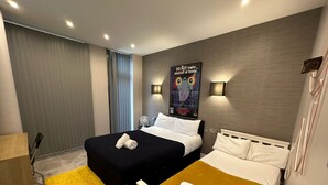 A hotel room with two beds, a yellow rug, a poster on the wall, and a desk with a chair. - Themed Stunning 1-bed Apartment in London (London)