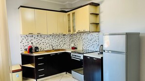 A compact kitchen with a stove, sink, and refrigerator, featuring a tiled backsplash and modern cabinetry. - EasyTrip Family - 2 bedrooms - City Center_417 (Divjakë)
