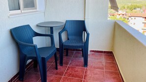 A balcony with two blue plastic chairs and a small round table. - EasyTrip Family - 2 bedrooms - City Center_417 (Divjakë)