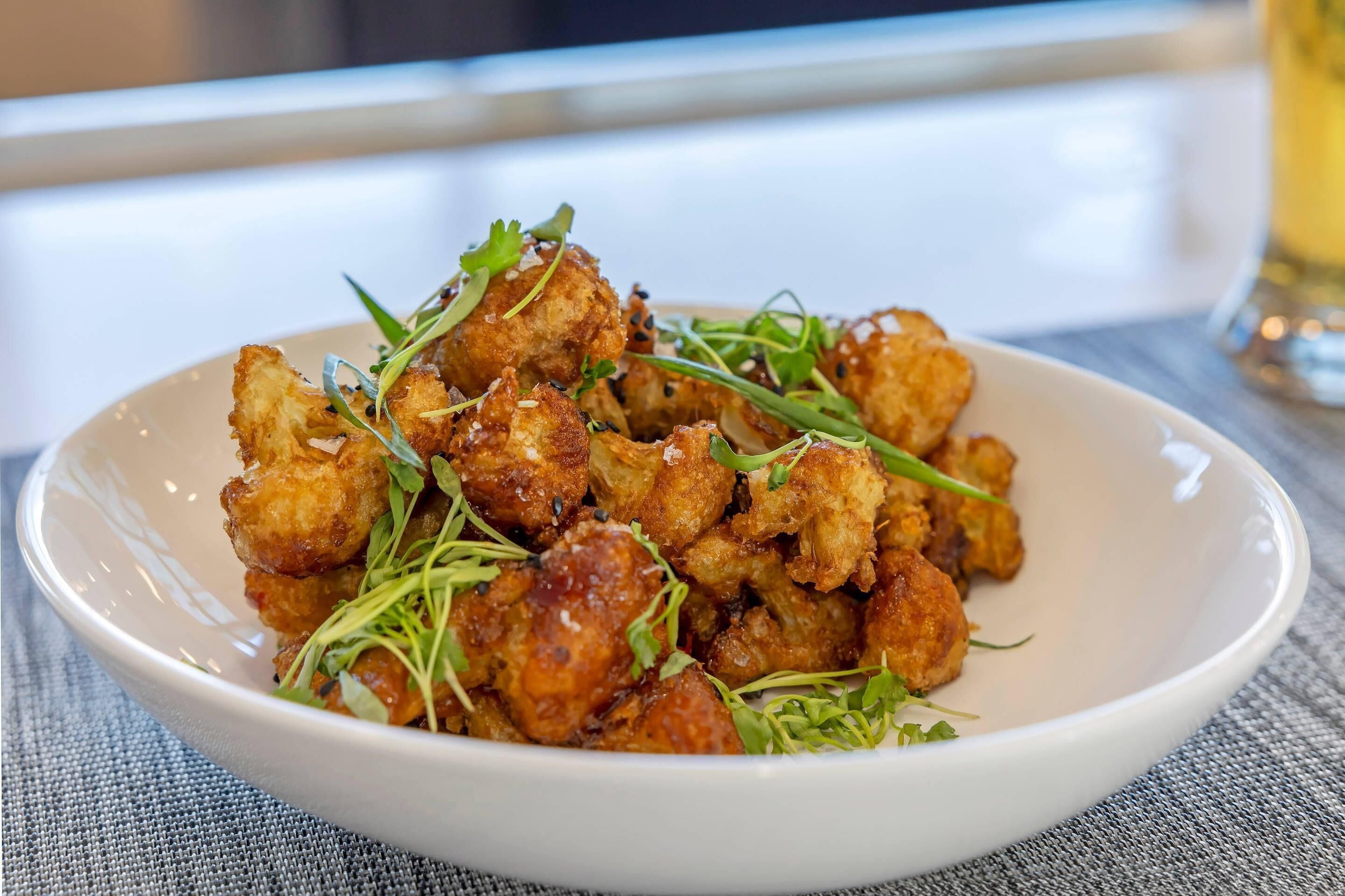 Un plato de pollo frito, adornado con vegetales verdes.