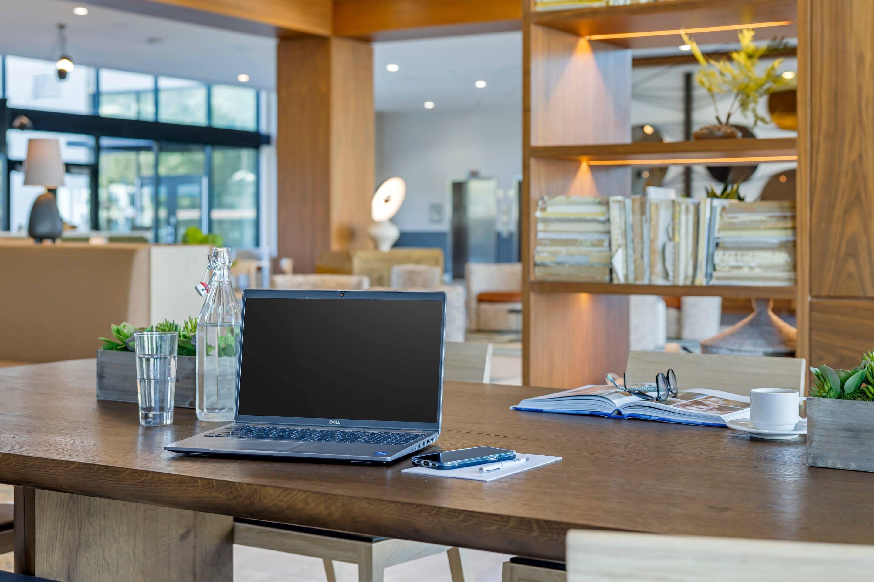 Un espacio de trabajo moderno con una computadora portátil, libros y una taza de café sobre una mesa de madera.