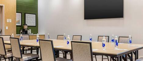 A conference room with a large table, chairs, a projector screen, and water bottles.