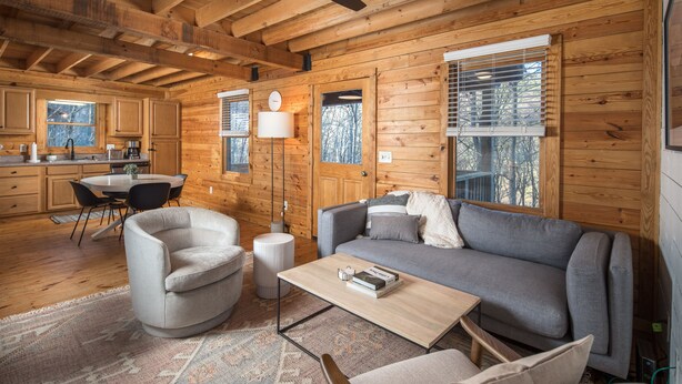 Een knus blokhutinterieur met houten details, een bank, een bijzettafeltje en een eethoek.