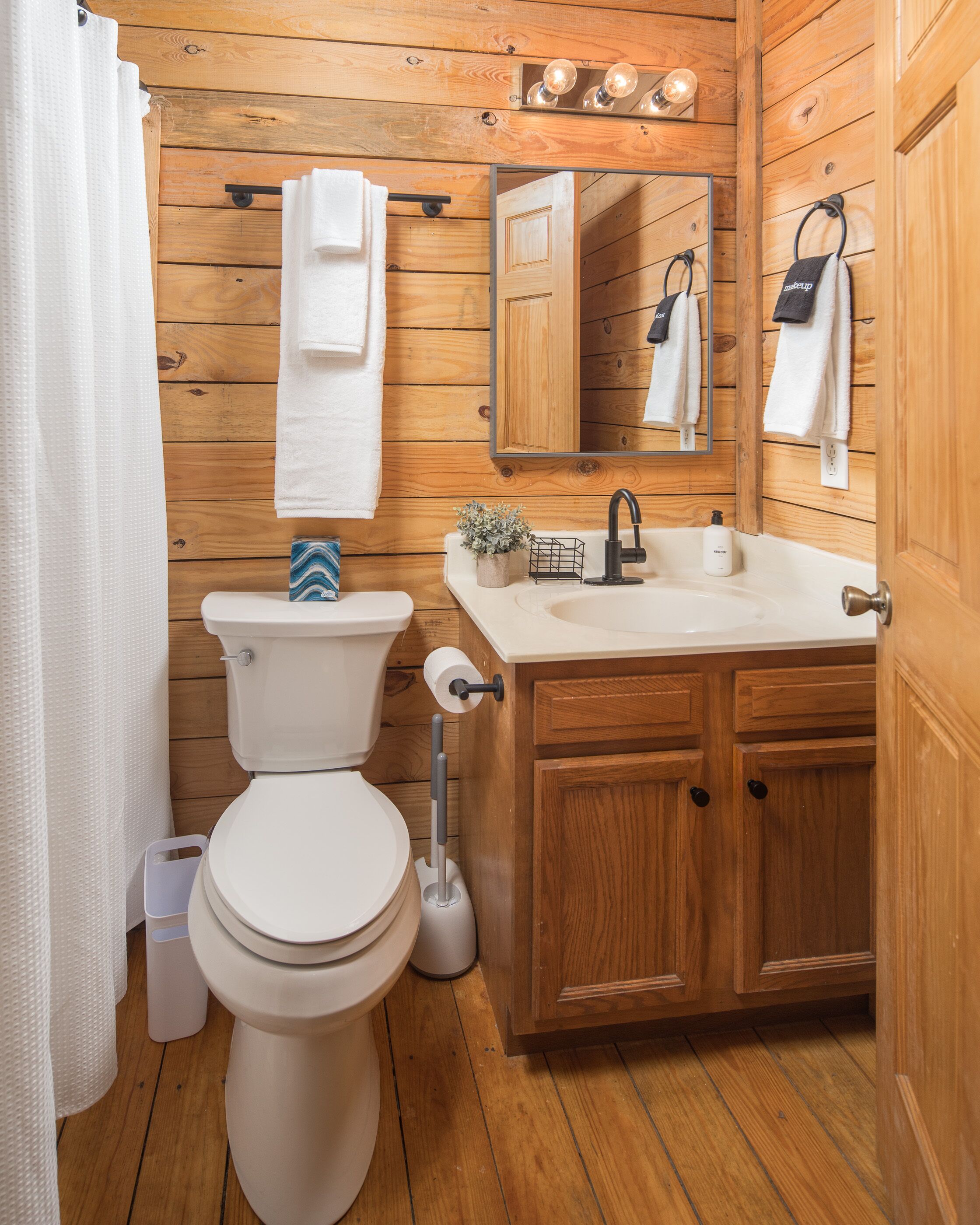 Une salle de bain en bois avec des toilettes, un lavabo et un miroir.