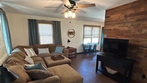 A living room with a sofa, ottoman, wooden coffee table, and a fireplace. - Harlan County Lake Retreat (Republican City)