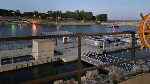 A marina with boats docked, a wooden ship's wheel, and a dock with a covered area. - Harlan County Lake Retreat (Republican City)