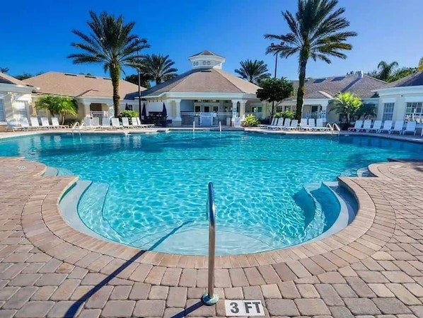 A swimming pool with lounge chairs, palm trees, and a building with a dome roof.