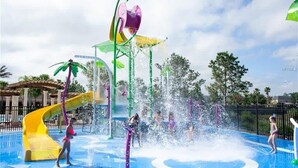 Un parco acquatico con uno scivolo giallo e getti d'acqua.