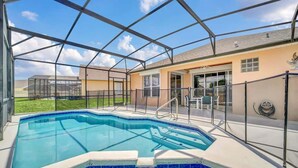 Piscina com estrutura de vidro, área de varanda coberta e uma casa com garagem.