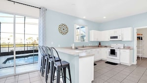 A modern kitchen with white cabinets, a central island, and a large window overlooking a pool. - Wonderful Lake View Vacation Getaway (Davenport)