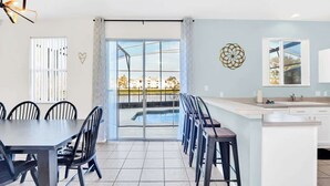 A modern kitchen with a large island, a dining area with a table and chairs, and a view of a swimming pool through a glass door. - Wonderful Lake View Vacation Getaway (Davenport)