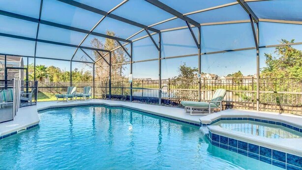 An indoor swimming pool with clear glass walls, surrounded by lounge chairs and a fenced area. - Wonderful Lake View Vacation Getaway (Davenport)