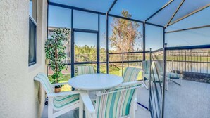 A covered patio with a round table and striped chairs, large windows, and a view of the outdoors. - Wonderful Lake View Vacation Getaway (Davenport)