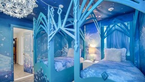 A bedroom with a blue theme, featuring a canopy bed and a nightstand.