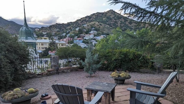 An outdoor patio with Adirondack chairs, a table, and a fire pit.