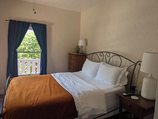 A bedroom with a bed, a nightstand, a dresser, a window with curtains, and a balcony view. - Central Location and Spectacular Views - Unit 2! (Bisbee)