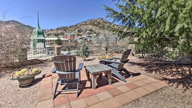An outdoor patio with Adirondack chairs and a table, a cactus planter, and a view of a town with a green church steeple. - Central Location and Spectacular Views - Unit 2! (Bisbee)