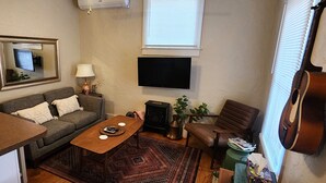 A cozy living room with a sofa, coffee table, TV, fireplace, and a guitar. - Central Location and Spectacular Views - Unit 2! (Bisbee)