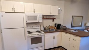 A compact kitchen with white cabinetry, a microwave, stove, and refrigerator. - Central Location and Spectacular Views - Unit 2! (Bisbee)