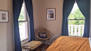 A bedroom with a bed, a chair, a window with curtains, an air conditioner, and a ceiling fan. - Central Location and Spectacular Views - Unit 2! (Bisbee)