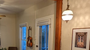 A cozy living room with a wooden floor, a round table, a guitar, and a framed picture on the wall. - Central Location and Spectacular Views - Unit 2! (Bisbee)