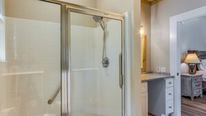 Een moderne badkamer met een glazen douchecabine, witte betegelde wanden en een houten vloer.