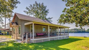 Een vakantiehuis aan het meer met een overdekte veranda, een terras en een bootje in de buurt.