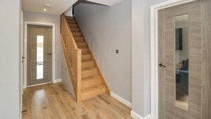 Un escalier avec des marches en bois et une rampe, menant à une pièce dotée d’une porte qui comporte un miroir et une petite fenêtre.