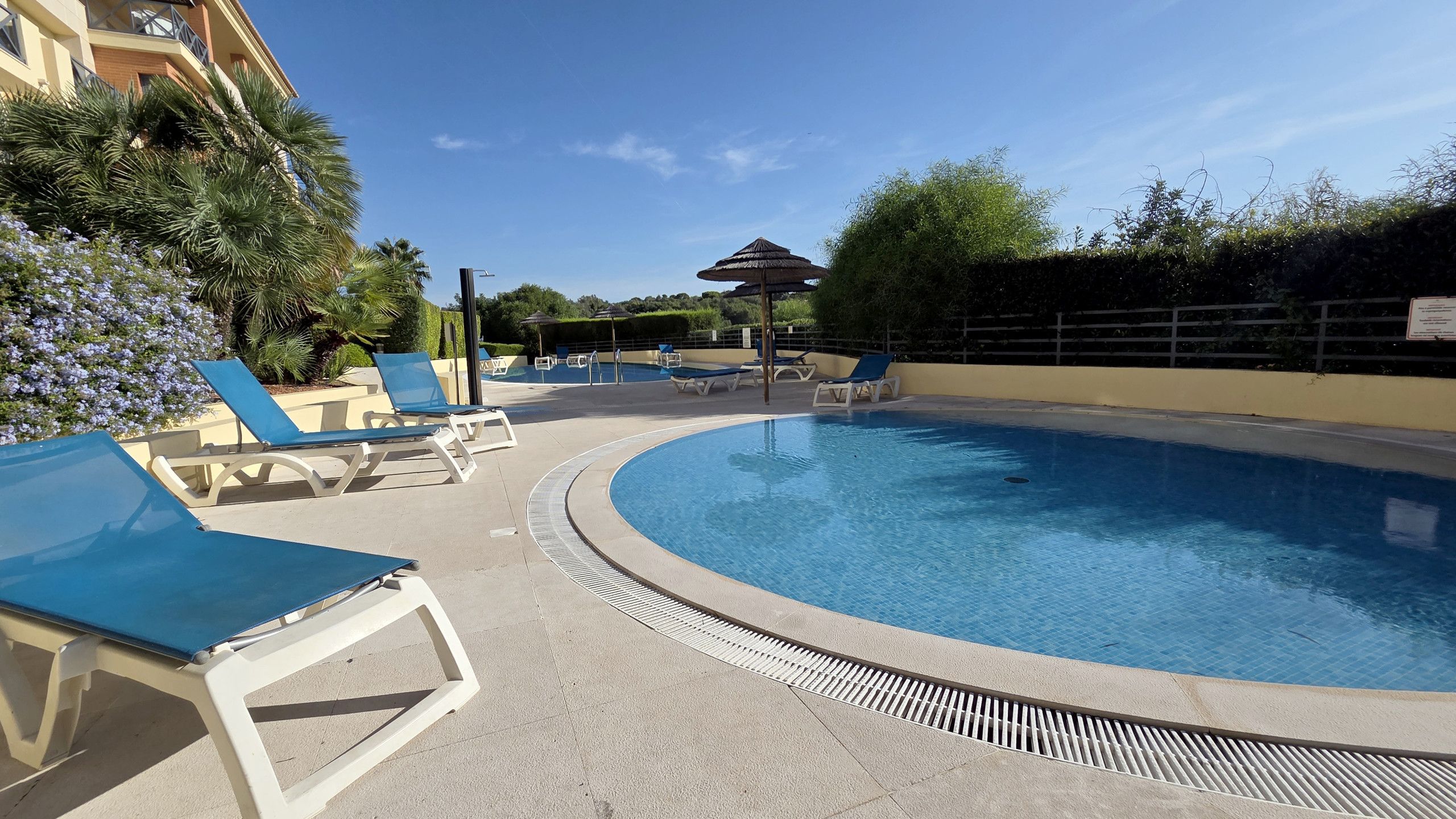 A swimming pool with lounge chairs and a covered area.