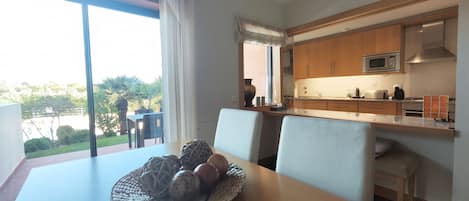 A modern kitchen with wooden cabinets, a microwave, and a dining area with a table and chairs.