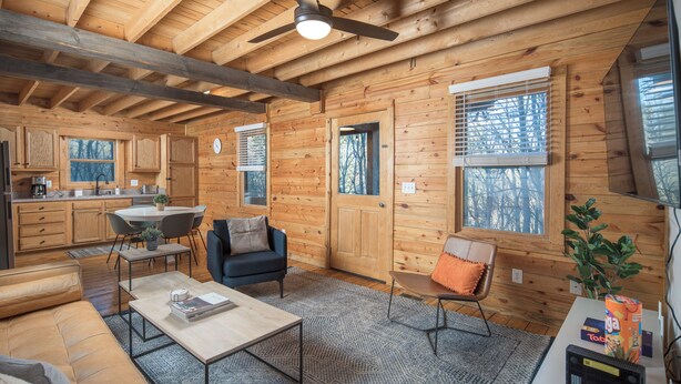 A log cabin interior with a kitchen, living area, and large windows.