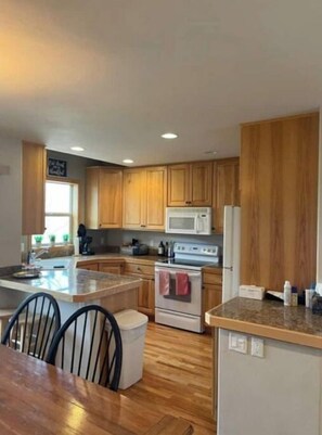 Enjoy cooking in this well-equipped kitchen with a central island, stainless steel stove, microwave, and refrigerator.