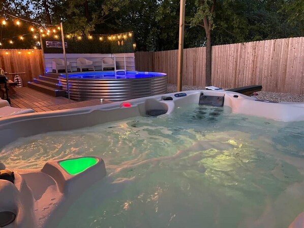 A hot tub area with a wooden deck, a covered seating area, and a sign that reads 'OUR POOL'.