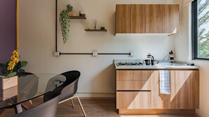 Una cuina moderna amb armaris de fusta, una placa de gas i una finestra que deixa entrar llum natural.