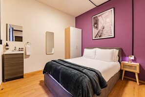 Une chambre à coucher comprenant un lit, une commode, un miroir, une armoire et une table de chevet avec une lampe.