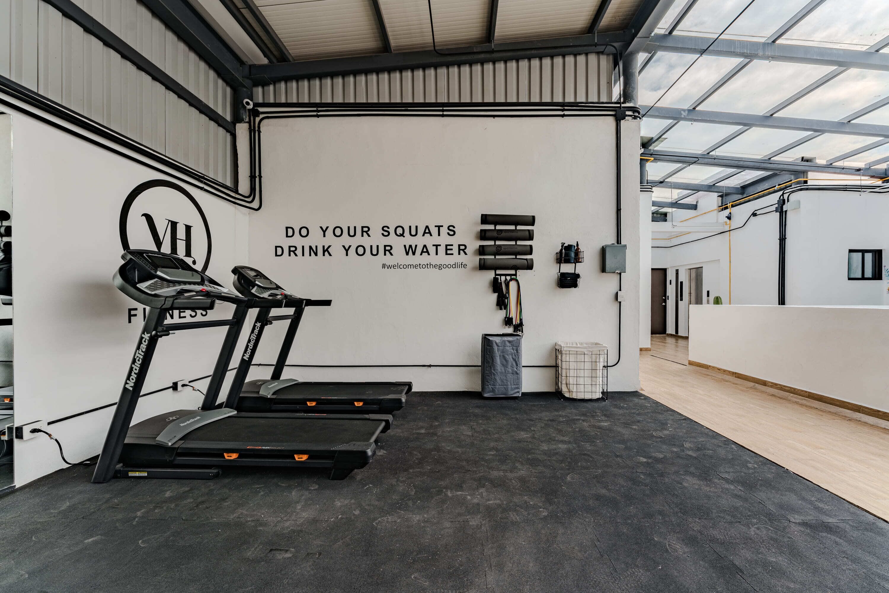 Een sportschool met loopbanden, een muur met motiverende tekst en fitnessapparatuur.