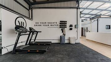 Een sportschool met loopbanden, een muur met motiverende tekst en fitnessapparatuur.