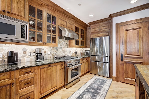 Enjoy cooking in this well-equipped kitchen with stainless steel appliances, granite countertop, and wooden cabinetry.