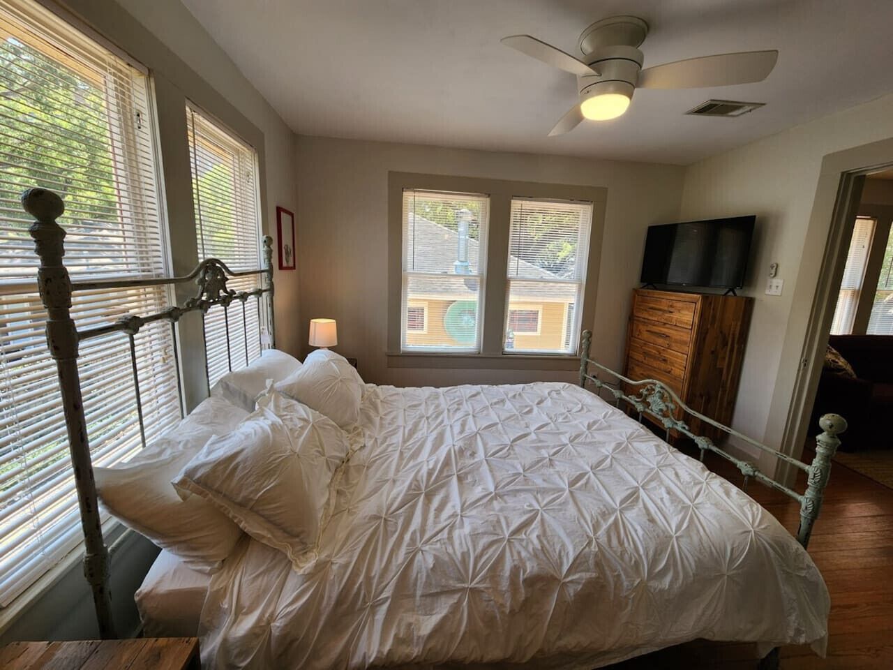 Ein Schlafzimmer mit Bett, Deckenventilator, Kommode und Fernseher.