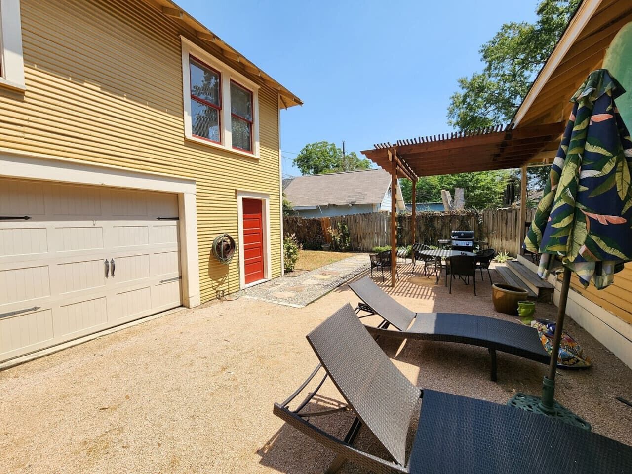 A residential backyard with a covered patio, a barbecue grill, and outdoor seating.