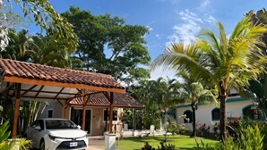A white car parked in front of a building with a tiled roof and a covered porch. - Vibrant Home with Pool, Perfect Beachside Getaway (Esterillos Oeste)