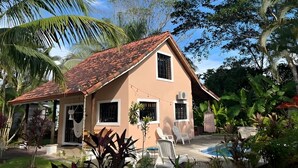 A two-story house with a tiled roof, a small front porch, and a swimming pool. - Vibrant Home with Pool, Perfect Beachside Getaway (Esterillos Oeste)