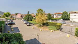 A parking lot with cars and a gated entrance, surrounded by residential buildings and greenery. - San Concordio Blue -Affitti Brevi Italia (Lucca)