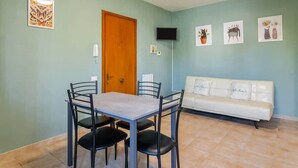 Un espace repas comprenant une table et des chaises, un canapé et des œuvres d’art murales.