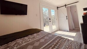 Makuuhuoneessa on sänky, seinälle asennettu televisio ja liukuovi, joka johtaa ulkotilaan.
