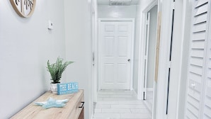 A hallway with a wooden bench, a potted plant, and a sign that reads "The Beach Fixes Everything." - Cozy retreat, NE cape coral oasis 5 mins to restaurants and shopping plaza. (Cape Coral)