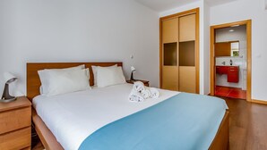 Una habitación de hotel con cama, mesita de noche, lámpara, toalla y armario.