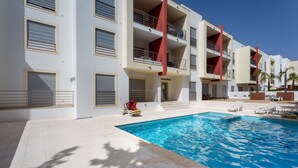 Un hotel moderno con piscina, varios balcones y una terraza.