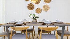 A dining table set with white plates and bowls, surrounded by wooden chairs with grey cushions. - Special Offer Resort style & free Waterpark 1150 (Kissimmee)